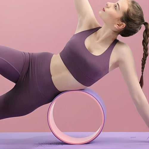 Femme accôtée avec sa hanche sur roue de yoga violet rose yoga zenitude